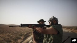 A rebel fighter checks a rifle at a checkpoint between Tarhouna and Bani Walid. Moammar Gadhafi is determined to fight his way back to power, the toppled dictator's spokesman said but a large convoy of his soldiers has apparently deserted, crossing the Li