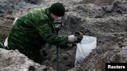 A soldier from a special "search battalion" of Belarus Defense Ministry takes part in the exhumation of a mass grave containing the remains of about 730 prisoners of a former Jewish ghetto, discovered at a construction site in the center of Brest, Feb. 26, 2019.