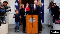 Former Australian prime minister Malcolm Turnbull kisses his wife, Lucy, while standing with daughter Daisy, and grandchildren Alice and Jack after a news conference in Canberra, Australia, Aug. 24, 2018. Turnbull resigned from Parliament Friday, triggering an election.