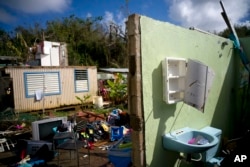 FILE - In this Oct. 14, 2017, photo, what was once the home Arden Dragoni and his family lies in ruins after the passing of Hurricane Maria in Toa Baja, Puerto Rico.