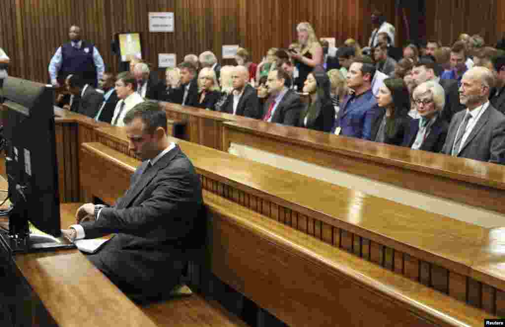 Oscar Pistorius looks at the time as he sits in court ahead of his trial at the North Gauteng High Court in Pretoria, March 3, 2014. 