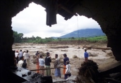 Warga berdiri di dekat sungai yang banjir di Mojokerto, Jawa Timur, menyusul hujan deras di wilayah tersebut pada Rabu, 4 Februari 2004. (Foto: REUTERS/Sigit Pamungkas)