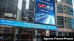 FILE - People walk beneath a welcome message for Chinese artificial intelligence startup SenseTime after its listing on the stock exchange in Hong Kong, Dec. 30, 2021.