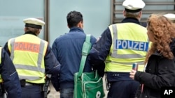 La police mène loin un homme à la gare principale , le 12 janv 2016, à Cologne , en Allemagne .Les vols et agressions sexuelles du Nouvel An à Cologne ont été attribués en grande partie aux étrangers et ont poussé la discussion sur la crise migratoire .