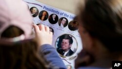 FILE - Michelle (R) and Matilda Chipperfield of England look at photos of U.S. Presidents while visiting Dealey Plaza in downtown Dallas, Oct. 25, 2017. 