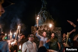 FILE - White nationalists participate in a torch-lit march on the grounds of the University of Virginia ahead of the Unite the Right Rally in Charlottesville, Va., Aug. 11, 2017.