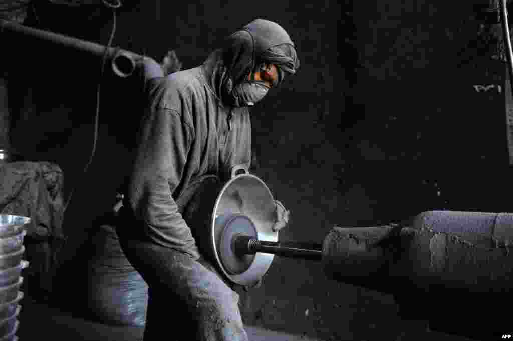 An Afghan laborer polishes a metal pot at an aluminium workshop in Herat.