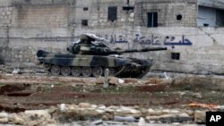 Tank tentara Suriah di depan dinding bertuliskan "Aleppo adalah ibukota budaya" di Tariq al-Bab, Aleppo timur (3/12). (AP/Hassan Ammar)