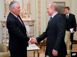 FILE - Russian Prime Minister Vladimir Putin, right, shakes hands with Rex W. Tillerson, chairman and chief executive officer of Exxon Mobil Corporation at their meeting in the Novo-Ogaryovo residence outside Moscow, Monday, April 16, 2012. Exxon is teaming up w