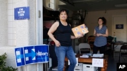 Cynthia Ameli, center, a Chinese-American, picks up materials from Sarah Gibson before heading out to canvass for presidential candidate Hillary Clinton in Las Vegas, Feb. 12, 2016.