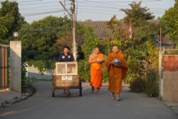 Buddhist monks at Pa Book Temple in Lamphun, Thailand, use a mobile food cabinet to collect alms.