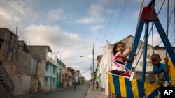 FILE - Children play on a swing in Santiago, Cuba, March 21, 2015.