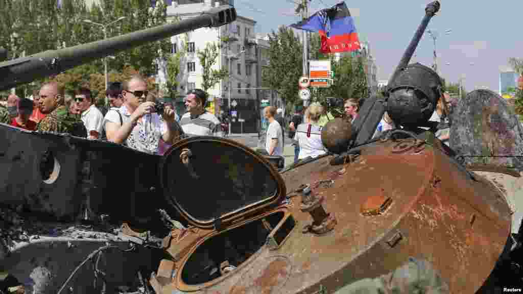 A man takes photos of destroyed Ukrainian army vehicles that were seized and put on public display at the central square in Donetsk, Ukraine, Aug. 24, 2014. 