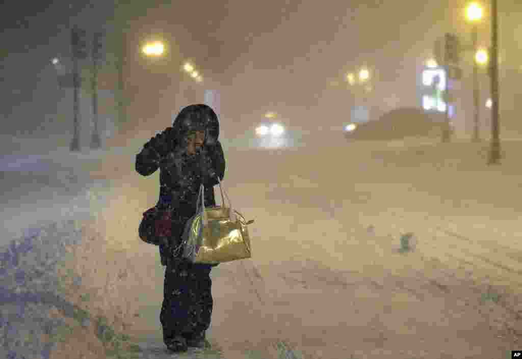 Denise Young of Lynnfield, a nursing supervisor at Massachusetts General Hospital, adjusts her hood while walking to work in Boston. A storm packing blizzard conditions spun up the East Coast, pounding coastal eastern Long Island into Maine with high winds and heavy snow.