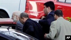 Surrounded by security forces, U.S. government contractor Alan Gross, left, arrives to a courthouse to attend a trial in Havana, Cuba, Saturday March 5, 2011.