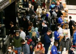 Travelers wait to process through a security checkpoint at Seattle-Tacoma International Airport before the Thanksgiving holiday in Seattle, Washington, Nov. 24, 2021.