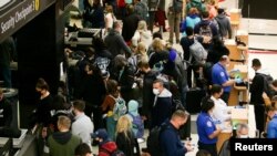Travelers wait to process through a security checkpoint at Seattle-Tacoma International Airport before the Thanksgiving holiday in Seattle, Washington, Nov. 24, 2021.