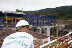 FILE - A Lao worker rests near to the Nam Theun 2 power dam's powerhouse under construction 28 June 2007 in Laos' Nakai plateau.