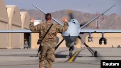 A U.S. airman guides a U.S. Air Force MQ-9 Reaper drone as it taxis to the runway at Kandahar Airfield, Afghanistan, March 9, 2016. 