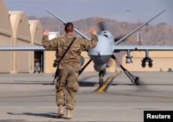 FILE - A U.S. airman guides a U.S. Air Force MQ-9 Reaper drone as it taxis to the runway at Kandahar Airfield, Afghanistan, March 9, 2016.