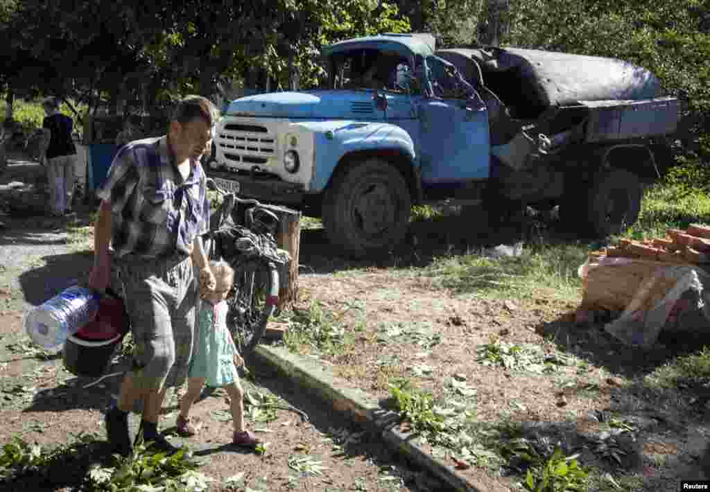 A man and his daughter walk to a pumping station to get water in the eastern Ukrainian city of Slovyansk, July 1, 2014.