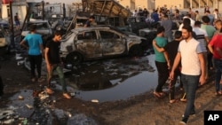 People gather at the scene of a deadly car bombing in the Habibiya neighborhood of Sadr City, Baghdad, Iraq, Aug. 15, 2015. 