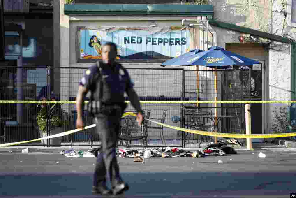 Un policía camina frente al bar Ned Peppers, en Dayton, Ohio, escenario de un tiroteo masivo, ocurrido menos de 24 horas de uno anterior en El Paso, Texas. Nueve personas murieron en el ataque de Ohio, además del responsable que fue abatido por la policía.&nbsp;(AP Photo/John Minchillo)