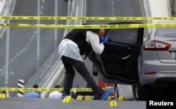 A police investigator takes pictures of a vehicle after an attack on a police station in Istanbul, Turkey, Aug.10, 2015.