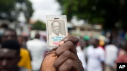 A supporter of Haiti's former President Jean-Bertrand Aristide and presidential candidate Maryse Narcisse, of the Fanmi Lavalas political party, holds up a picture of Jean Bertrand Aristide in Petion-Ville, Haiti, Aug. 29, 2016. 