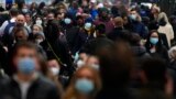 FILE - Shoppers wearing face coverings walk down Oxford Street, Europe's busiest shopping street, in London, Dec. 23, 2021. Scientists are seeing signals that COVID-19′s omicron wave may have peaked in Britain.