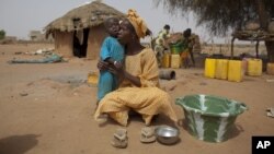 Maryam Sy comforts her 2-year-old son Aliou Seyni Diallo, the youngest of nine, after a neighbor gave him dry couscous to stop him from crying with hunger, May 1, 2012. 