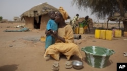 Maryam Sy comforts her 2-year-old son Aliou Seyni Diallo, the youngest of nine, after a neighbor gave him dry couscous to stop him from crying with hunger, May 1, 2012. 