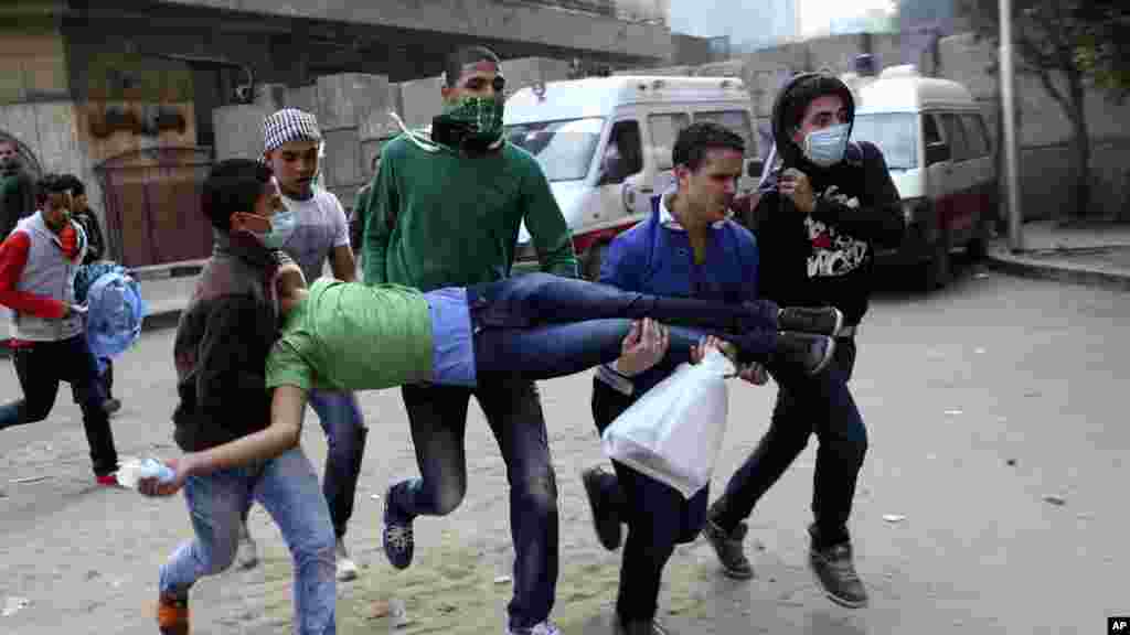 Egyptians carry a protester wounded in clashes with security forces near Tahrir square, where an opposition rally has been called for to voice rejection of President Morsi's seizure of near absolute powers in Cairo, Egypt, November 27, 2012.