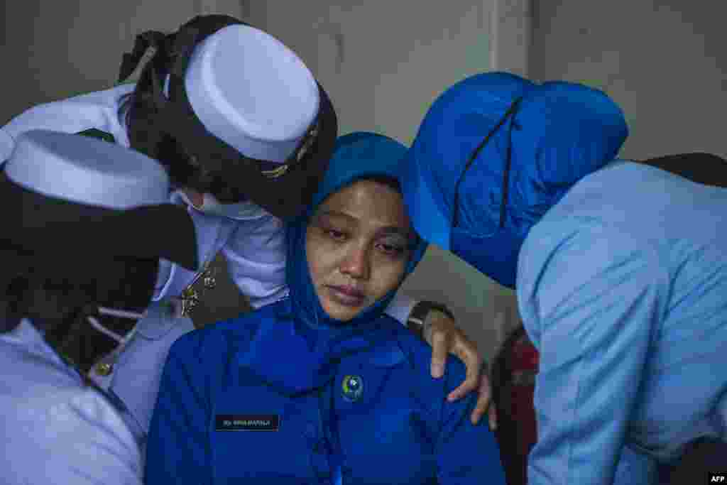 Military personnel console a sailor&#39;s wife during a remembrance ceremony for the crew of the Indonesian navy submarine KRI Nanggala that sank on April 21 during a training exercise, on the deck of the hospital ship KRI Dr. Soeharso off the coast of Bali.