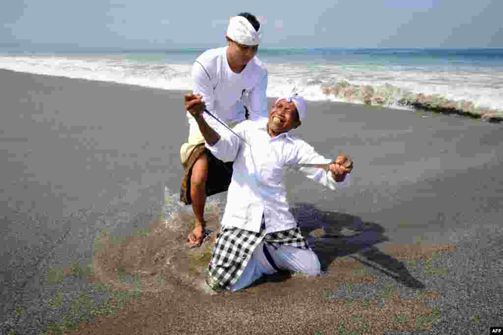 A Balinese man in a trance stabs himself with a &quot;keris&quot; traditional dagger as he attends a Melasti prayer ceremony at Petitenget beach in Kuta on Indonesia&#39;s resort island of Bali. Melasti is a purification festival which is held several days before &quot;Nyepi&quot;, a day of silence, when Hindus on the island of Bali are not allowed to work, travel or take part in any indulgence.