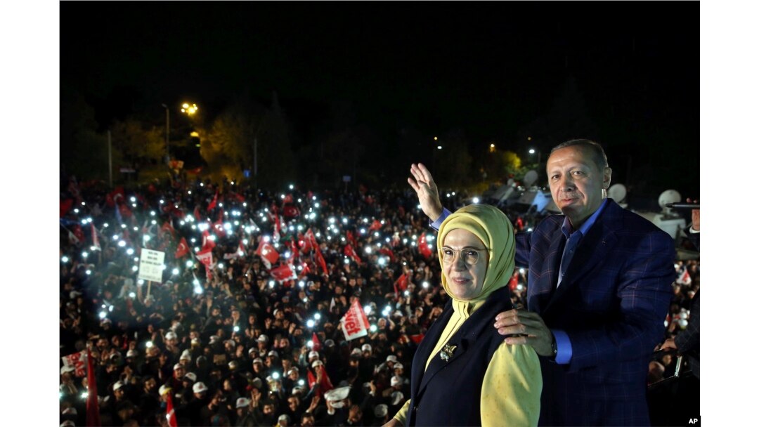 Turkey's President Recep Tayyip Erdogan and his wife Emine Erdogan pose for photos with cheering supporters in the background after unofficial referendum results were announced, in Istanbul, late Sunday, April 16, 2017.