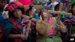 FILE - Indigenous women pray holding wooden crosses during a ceremony by human rights activists in front of the Supreme Court in Guatemala City, Feb. 25, 2016. The U.N. human rights office reports, May 18, 2018, the recent killing of several human rights defenders in Guatemala shows an alarming deterioration in the rule of law.