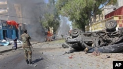 A Somali soldier stands near the burnt wreckage of a car, after an explosion, in Mogadishu Somalia, Oct. 1, 2016.