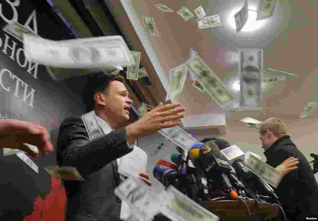 An unidentified person throws pieces of paper resembling banknotes, as Russian opposition figure Ilya Yashin (L) presents his report, titled &#39;National Security Threat&#39; and dedicated to the current situation in Chechnya and its leader Ramzan Kadyrov, in Moscow.