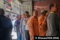 After voting, these men wait in line for bags of food or a small amount of money in Cairo on April 20, 2019.
