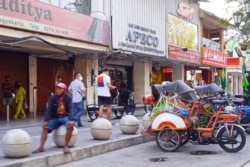 Tukang becak menanti penumpang di depan toko-toko yang tutup di Malioboro, Yogyakarta. (Foto: VOA/Nurhadi)