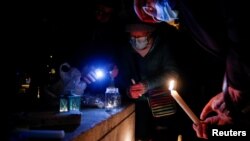 FILE - People light candles as they pay tribute to the 27 migrants who died when their dinghy deflated as they attempted to cross the English Channel, at the Richelieu Park in Dunkerque, France, Nov. 25, 2021. 