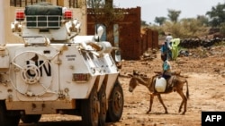 Seorang anak laki-laki Sudan menunggang keledai melintas di depan kendaraan Misi PBB-Uni Afrika (UNAMID) di Kota Golo yang dikoyak peran di wilayah Jebel Marra di Darfur tengah, 19 Juni 2017.
