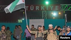 FILE - Fighters from the Kurdish People's Protection Units and Free Syrian Army's Al-Tahrir Brigade gesture while posing on the Syrian-Turkish border Tel Abyad of Raqqa governorate after they said they took control of the area, June 15, 2015.