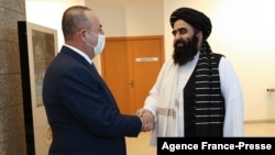 A handout picture released by Turkish Foreign ministry press office shows Turkish Foreign Minister Mevlut Cavusoglu, left, shaking hands with Taliban's acting Foreign Minister Amir Khan Muttaki their meeting in Ankara on Oct. 14, 2021.