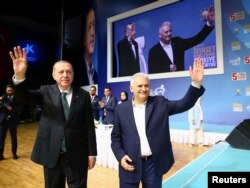 FILE - Turkish President Recep Tayyip Erdogan and Prime Minister Binali Yildirim greet their supporters during a meeting of the ruling AK Party in Istanbul, Turkey, April 29, 2018.