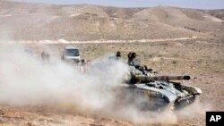Tentara pemerintah Suriah dengan tanknya mengambil posisi dekat gerbang masuk kota Palmyra, Suriah tengah (24/3).