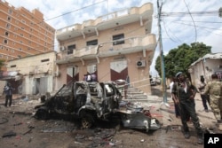 FILE - A Somali soldier stands on guard next to a destroyed car near a popular mall after a car bomb attack in Mogadishu, Somalia, July 30, 2017. The Somalia-based extremist group al-Shabab often carries out deadly bombings in Mogadishu.