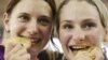 Germany's Kristina Vogel, right and teammate Miriam Welte, bite their gold medals after winning the women's team sprint track cycling event at the 2012 Summer Olympics, Aug. 2, 2012, in London. 
