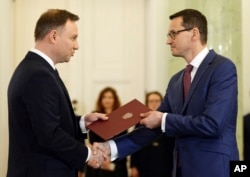 Polish President Andrzej Duda, left, formally designates Finance Minister Mateusz Morawiecki for the prime minister's post, in Warsaw, Poland, Dec. 8, 2017.